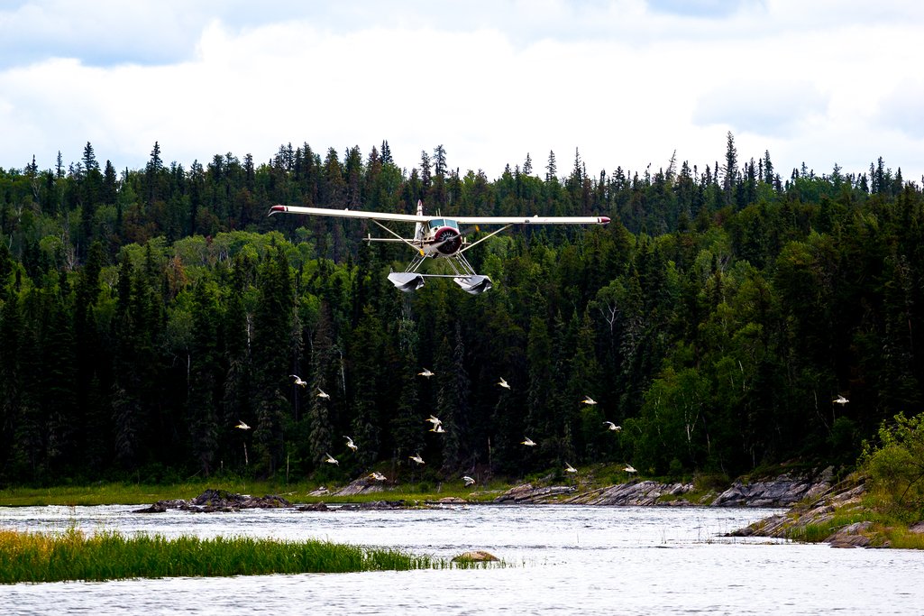 View of float plane flying just above water in northern Saskatchewan.