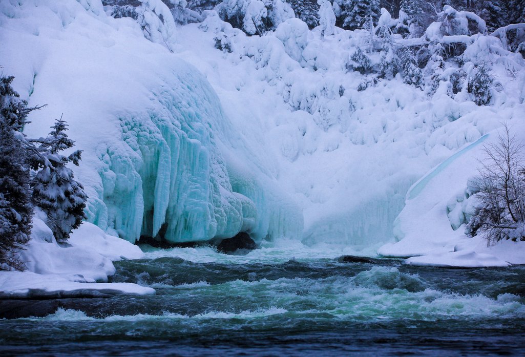 photo of frozen ice beside rapids on a river