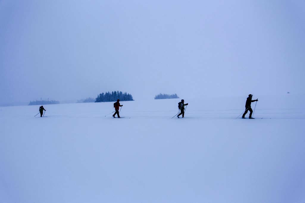 four people spaced apart cross-country skiing on a gloomy winter day