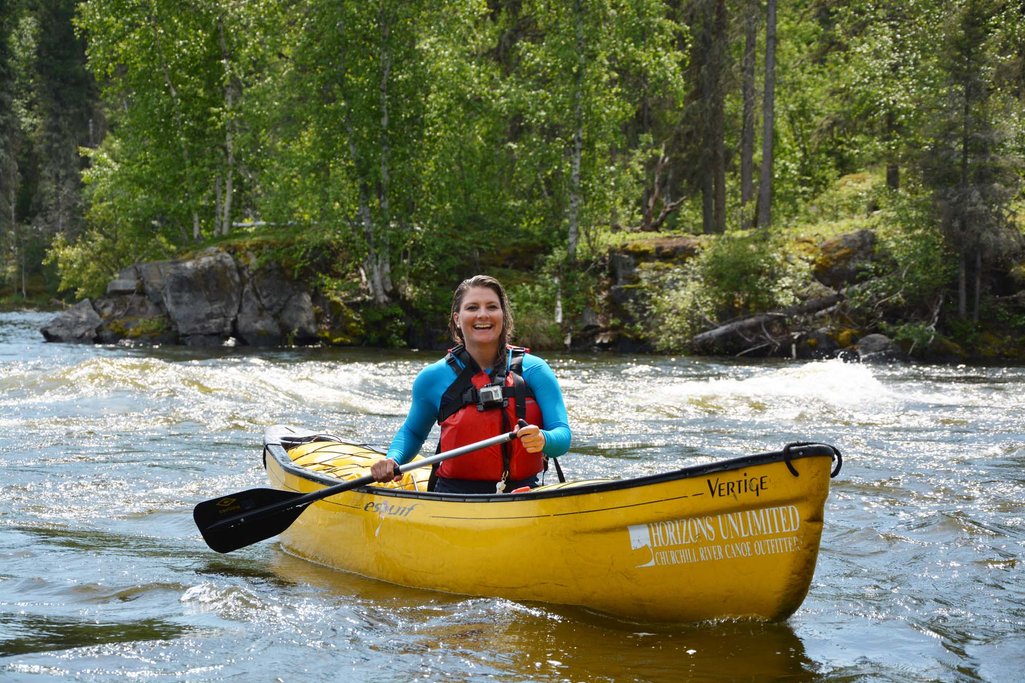 Photo of Ashlyn smiling while on the Churchill River in a yellow canoe