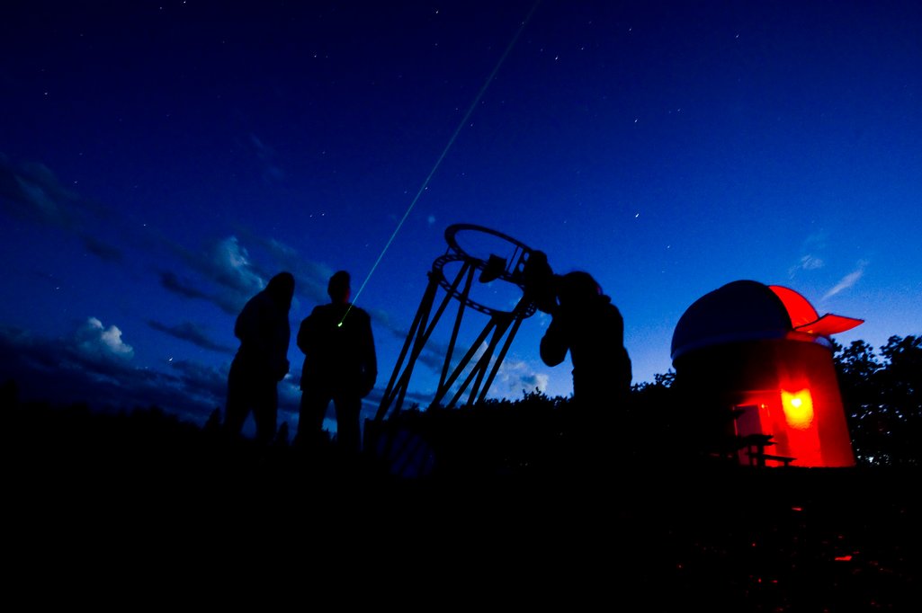 Astronomers pointer a laser pointer almost dark night sky beside telescopes