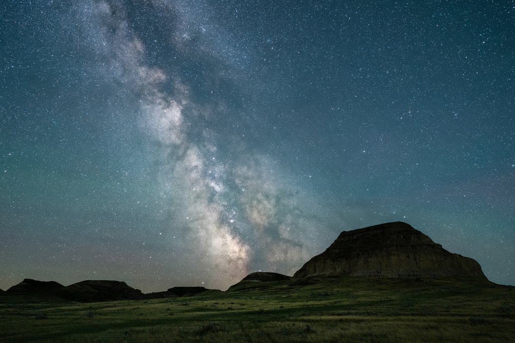 night photo of Saskatchewan badlands on a clear night with lots of stars and the milky way core stretching across the sky