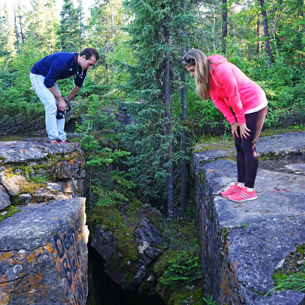 Two people standing on either side of a crevice looking down