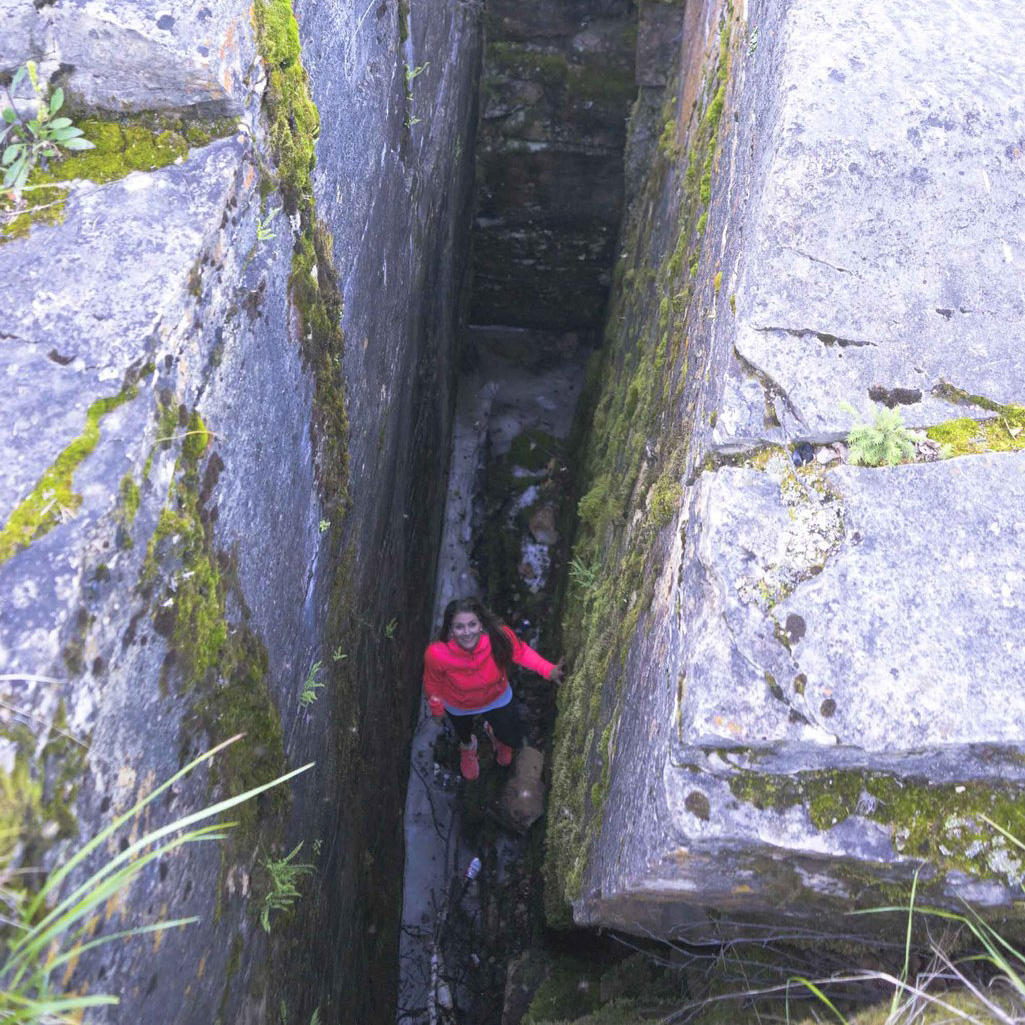 looking down into a limestone crevice and a person in a pink top is standing at the bottom