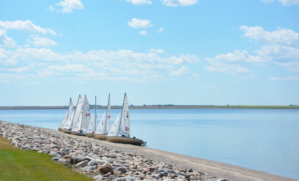 Photo of four sail boats resting on the shore of Lake Deifenbaker on a sunny summer day