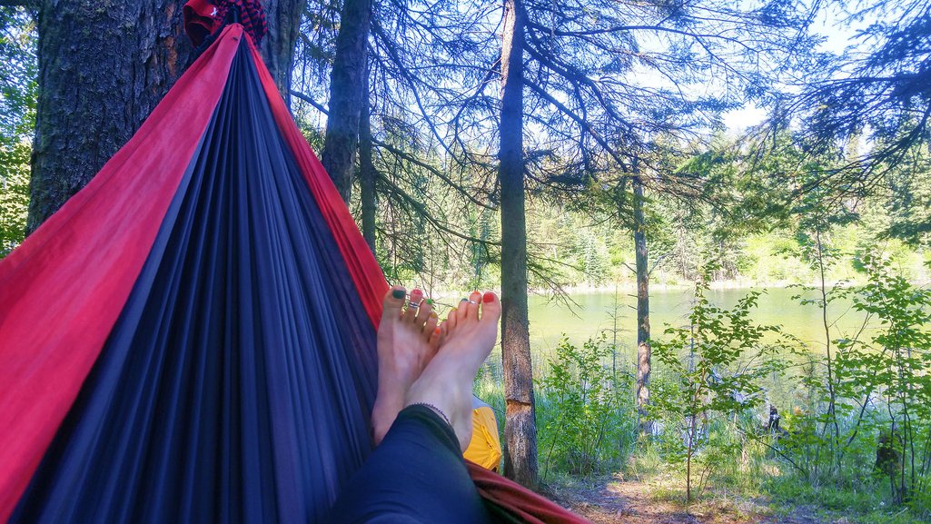 POV view of feet laying on a hammock in a forest