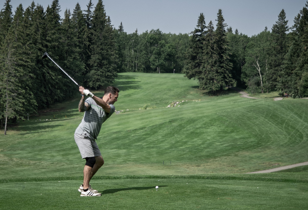 person mid swing teeing off at Kenosee golf course