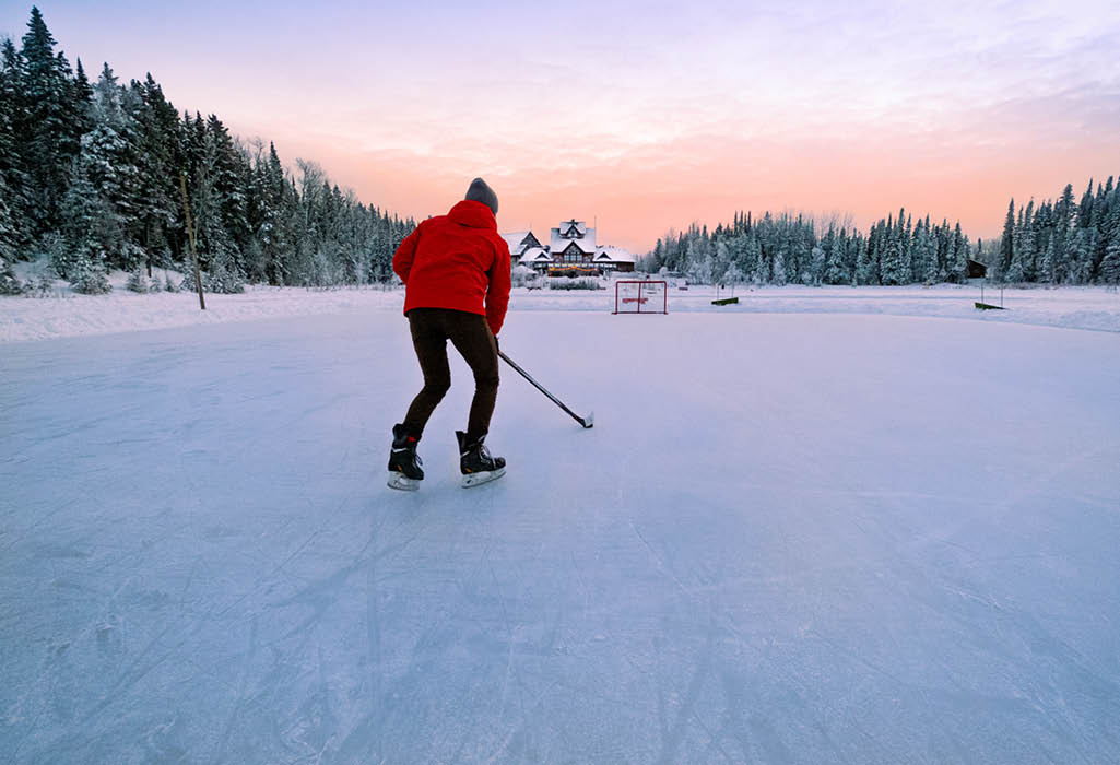 person playing hockey outside on frozen pond at elk ridge resort