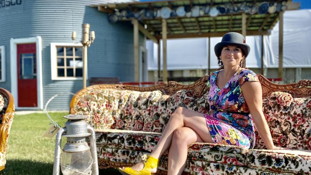 Picture of Erin Kinder sitting on a vintage couch outside at her antique grounds